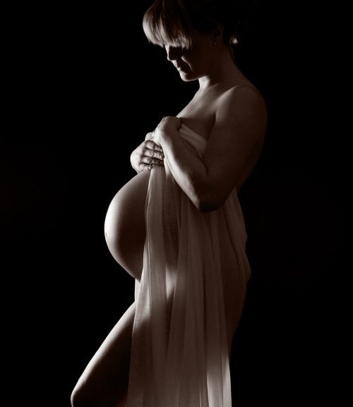 Unique Christmas Gift Maternity pregnancy portrait of pregnant woman in photography studio against a black background