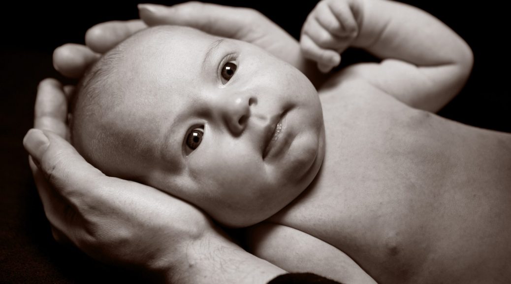 Black and white close up studio photo newborn baby in parents hands