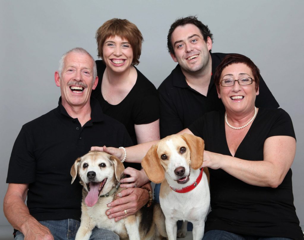 Family Portrait of parents and two adult children with two dogs in professional photography studio