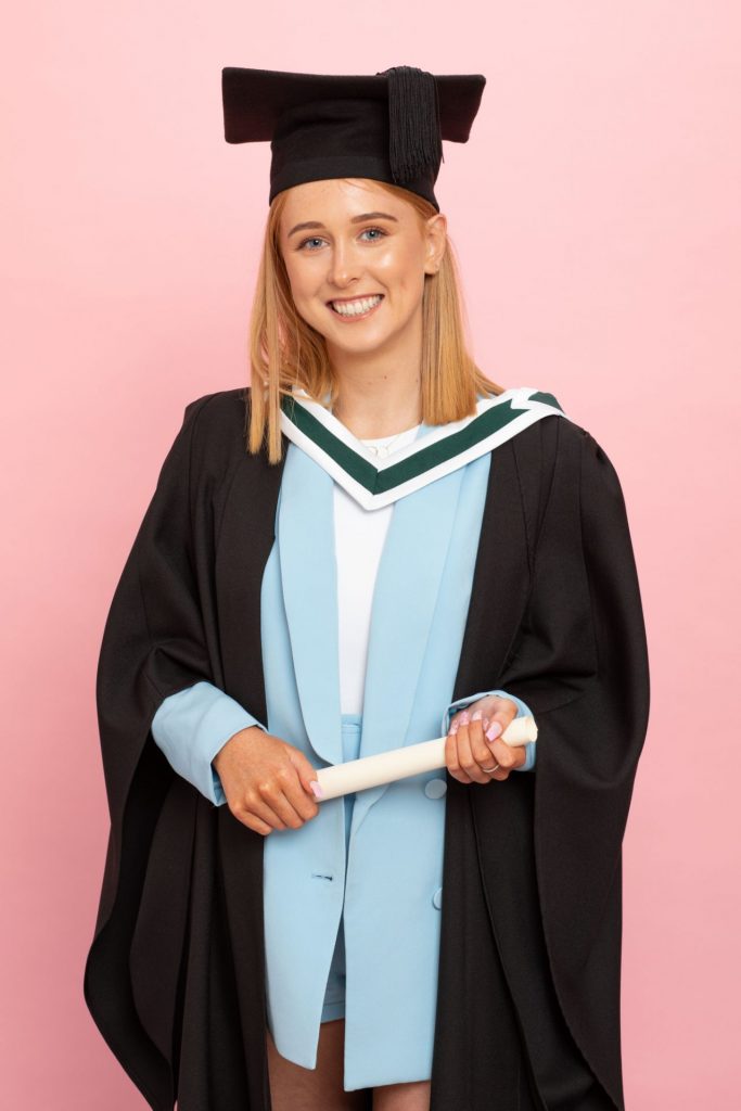 Graduation Photo for a Virtual Ceremony Portrait of young female graduate in baby blue suit, professional photography studio pink background