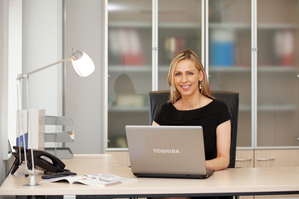Professional business portrait of female company director working at laptop in office environment 